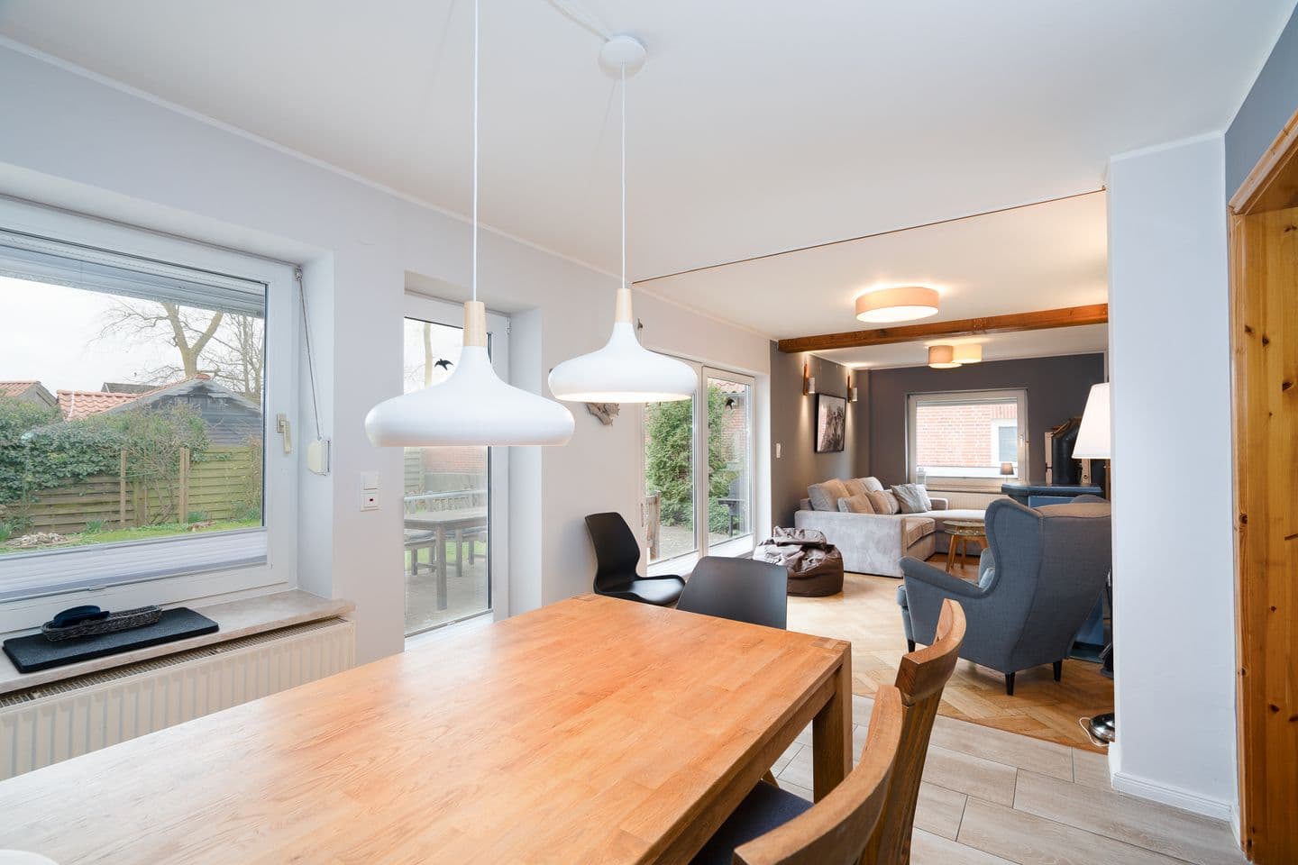 Die Wohnküche verfügt über einen Holztisch mit Stühlen, große Fenster und eine gemütliche Couch.