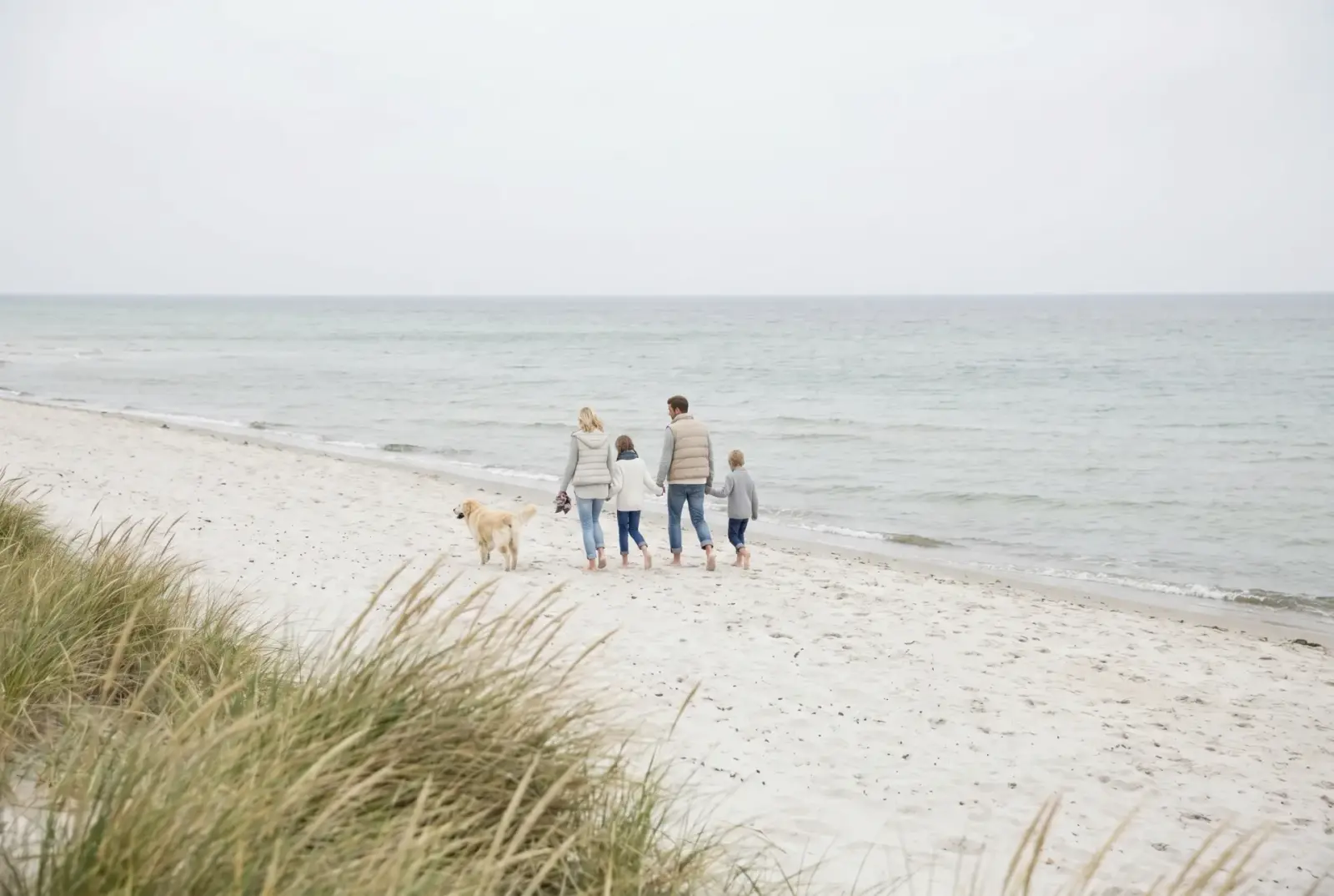 Familie macht einen Strandspaziergang mit Hund an der Ostsee
